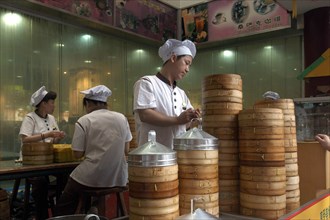 CHINA, Shanghai, Restaurant with stacked bamboo steamers and workers dressed in white