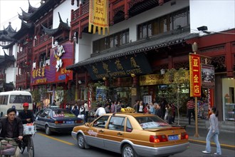 CHINA, Shanghai, Urban shopping street with passing traffic and pedestrians and traditional