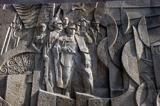 CHINA, Shanghai, Carved stone political mural depicting figures with guns with communist symbol