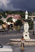 WEST INDIES, Guadeloupe, Basseterre, Large white statue in middle of street surrounded by houses