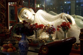 CHINA, Shanghai, Jade Buddha Temple. Reclining Buddha statue with flower vases in front