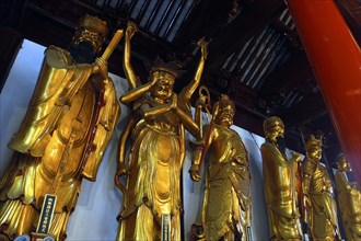 CHINA, Shanghai, Jade Buddha Temple. Row of standing golden statues of various figures
