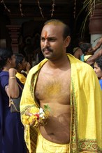 SINGAPORE, , Portrait of a man holding flowers and wearing yellow at an Indian Temple