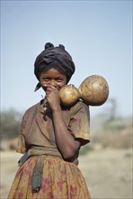 ETHIOPIA, Tribal People, Portrait of laughing Galla girl holding gourds.