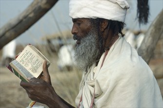 ETHIOPIA, Religion, Christian, Ethiopian Orthodox priest in Sudan reading from the Bible.