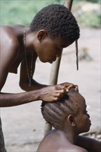 CONGO, Ituri Forest, Pygmy woman checking her daughters hair for head lice.