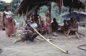 CONGO, Ituri Forest, Pygmy group with man smoking hallucinogens in long pipe.