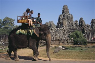 CAMBODIA, Siem Reap, Angkor Thom, Bayon Temple south facade with tourists on an elephant walking