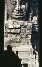 CAMBODIA, Siem Reap, Angkor Thom, Bayon Temple with a monk sitting in a doorway in front of one of