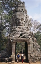 CAMBODIA, Siem Reap, Angkor, Ta Prohm monastic complex with tourists walking through the four faced