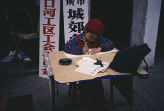 CHINA, Guangxi, Child practising calligraphy at desk.