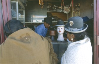 BOLIVIA, La Paz, El Alto, La Ceja.  Two women standing in front of hatmakers stall.