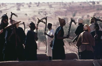 20049655 MALI  People Dogon rooftop dancers brandishing carved wooden staffs a symbol of a particular Dogon fraternity.