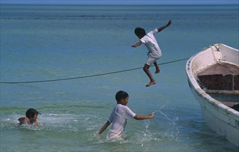 MEXICO, Yucatan, Celestun, Gulf of Mexico.  Children jumping from fishing boat into the sea.