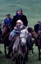 CHINA, Xinjiang Province, Kazakh mother and young child travelling on horseback