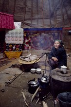 CHINA, Xinjiang Province, Altai Region, Kazakh woman inside her Kigizuy or yurt with covered stove