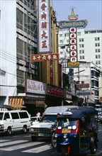 THAILAND, Bangkok, Street scene with tuk tuk and other traffic high rise buildings and advertising
