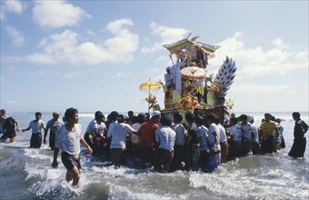 INDONESIA, Bali, Kuta, Cremation celebrations.  Crowds carrying cremation tower accompanied by