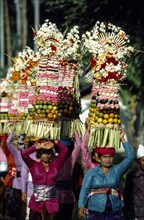 INDONESIA, Bali, Mengwi, Women carrying towers of fruit and flower offerings at Mengwi Festival.