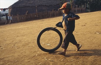 THAILAND, North, Chiang Rai , Akha child playing with bike tyre.