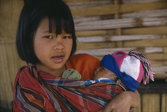 THAILAND, North, Chiang Rai , Lahu girl carrying baby in sling across her front.