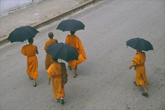 LAOS, Luang Prabang, Looking down on group of Buddhist monks carrying black umbrellas crossing