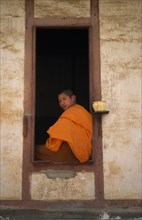 LAOS, Religion, Buddhism, Portrait of Therevaden Buddhist monk framed in window of building.