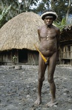 INDONESIA, Irian Jaya, Baliem Valley, Akima Village.  Dani tribesman wearing penis gourd.