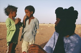 NIGER, Tribal People, Tuareg man looking towards two children.