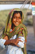 PAKISTAN, Sindh Province, Karachi, Smiling Sindhi gypsy girl wearing head dress.