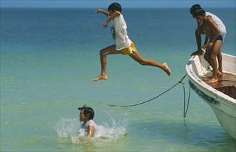 MEXICO, Yucatan, Celestun, Gulf of Mexico.  Children jumping from fishing boat into sea.