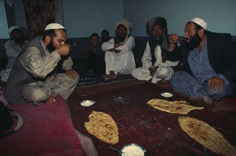 AFGHANISTAN, Kabul, Pashtun men eating traditional meal of bread and yoghurt.
