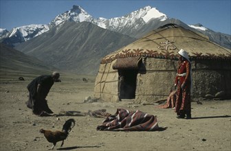 AFGHANISTAN, Nomadic People, Kirghiz nomads shaking out rugs beside yurt.