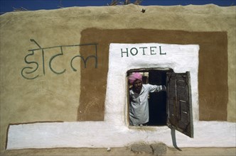 INDIA, Rajasthan, People, Man in turban looking out of low open doorway of village hotel.