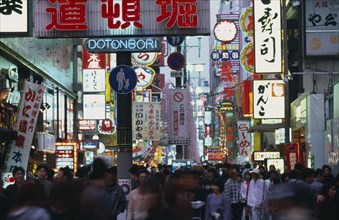 JAPAN, Honshu, Osaka, Dotonbori sign illuminated at dusk among mass of other neon signs with crowds