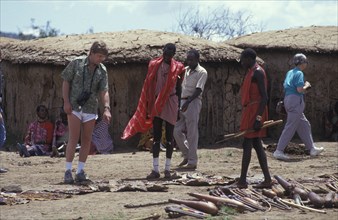 KENYA, , An American tourist haggles with a Maasai man in a cultural manyatta set up to interface