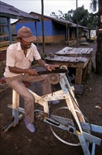 KENYA, Loitokitok, Man sharpening a knife on a pedal powered knife grinder