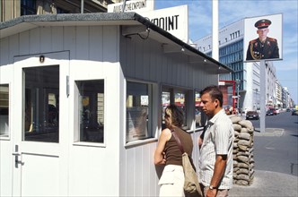 GERMANY, Berlin, Check Point Charlie with tourists looking through the hut window