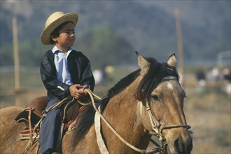 CHILE, Santiago, La  Barnechea, Young boy on horseback at the Fiesta de Cuasimodo held a week after