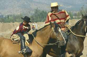 CHILE, Santiago, La  Barnechea, Man and young boy on horseback at the Fiesta de Cuasimodo held a