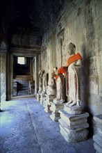 CAMBODIA, Angkor, View along row of Buddha statues draped in orange cloth at Angkor Wat