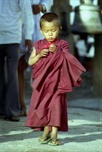 NEPAL, Kathmandu, Young novice monk walking through a street