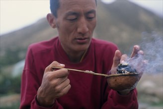 NEPAL, Mustang, Tibetan lama preparing incense for puja or prayer ceremony