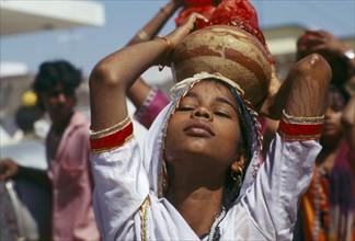 INDIA, Rajasthan, Udaipur, Young girl in trance carrying Holy Ganges water during memorial service.