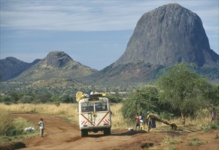 UGANDA, Karamoja, Minibus travelling along dirt road with people at the side