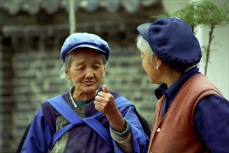 CHINA, Yunnan, Lijiang, Two elderly women talking in the street
