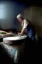 CHINA, Gansu, Langmusi, Smiling cook rolling pastry for an Apple Pie