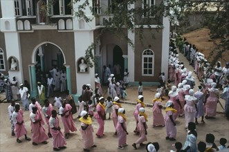 GHANA, Religion, Easter, Men and women in traditional pink dress leaving the Easter Sunday service