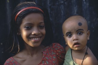 BANGLADESH, Dhaka, Young girl holding baby