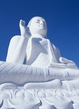 SRI LANKA, Mihintale, Angled view of large white seated Buddha seen from below looking up.